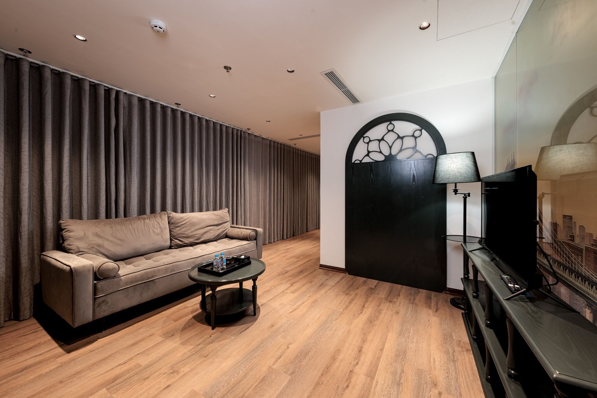 A modern living room with a sofa, a coffee table, a TV, and a decorative wall piece.