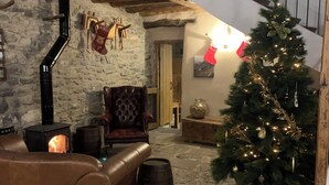A rustic interior with a stone fireplace, leather sofa, and a decorated Christmas tree. - Casa Lascorz (Ainsa)
