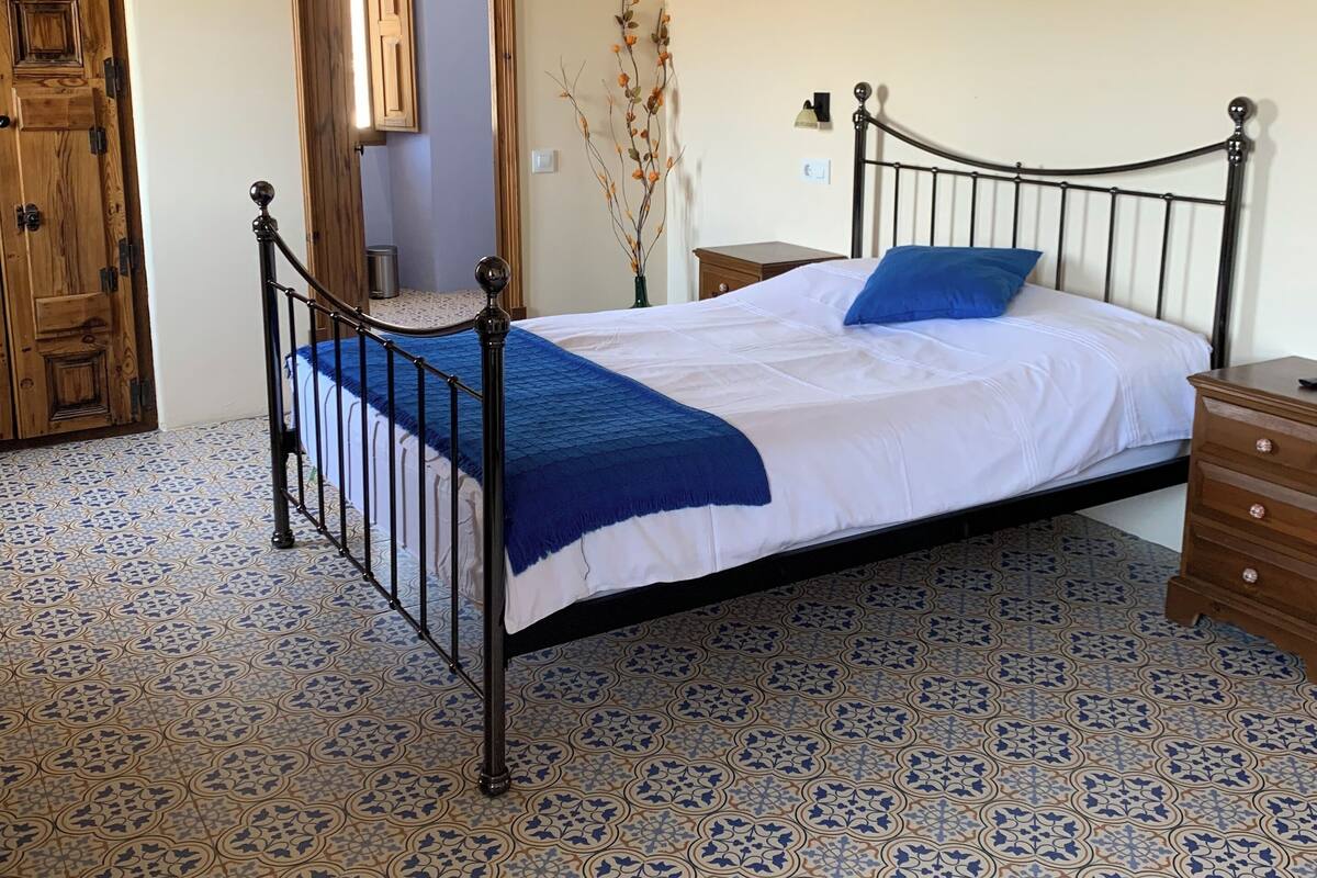 A bedroom with a bed, wooden door, and patterned floor.