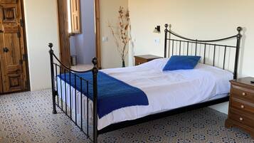 A bedroom with a bed, wooden door, and patterned floor.