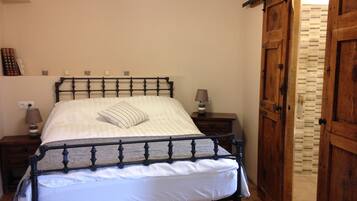 A bedroom with a bed, wooden wardrobe, and a nightstand with a lamp.