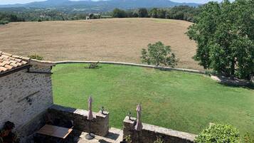 En byggnad i sten med en uteplats som har utemöbler och planterade blommor i krukor.