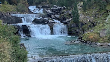 A natural waterfall surrounded by forested mountains.