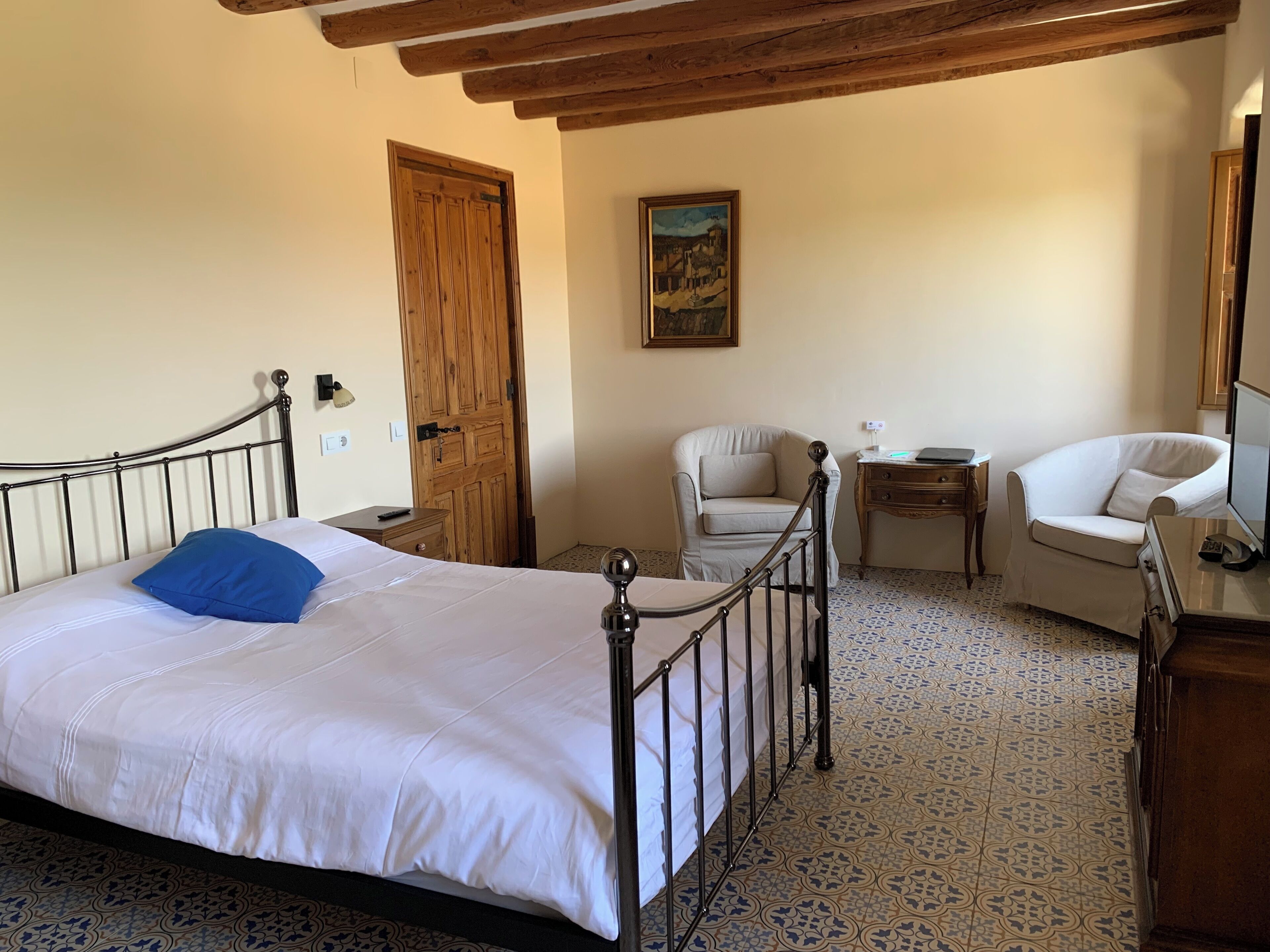 A bedroom with a bed, a chair, a desk, and a door.