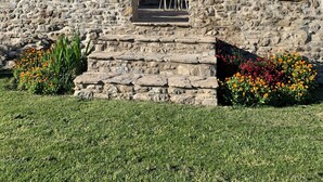 A stone building with a balcony, steps leading up to the entrance, and outdoor seating. - Casa Lascorz (Ainsa)