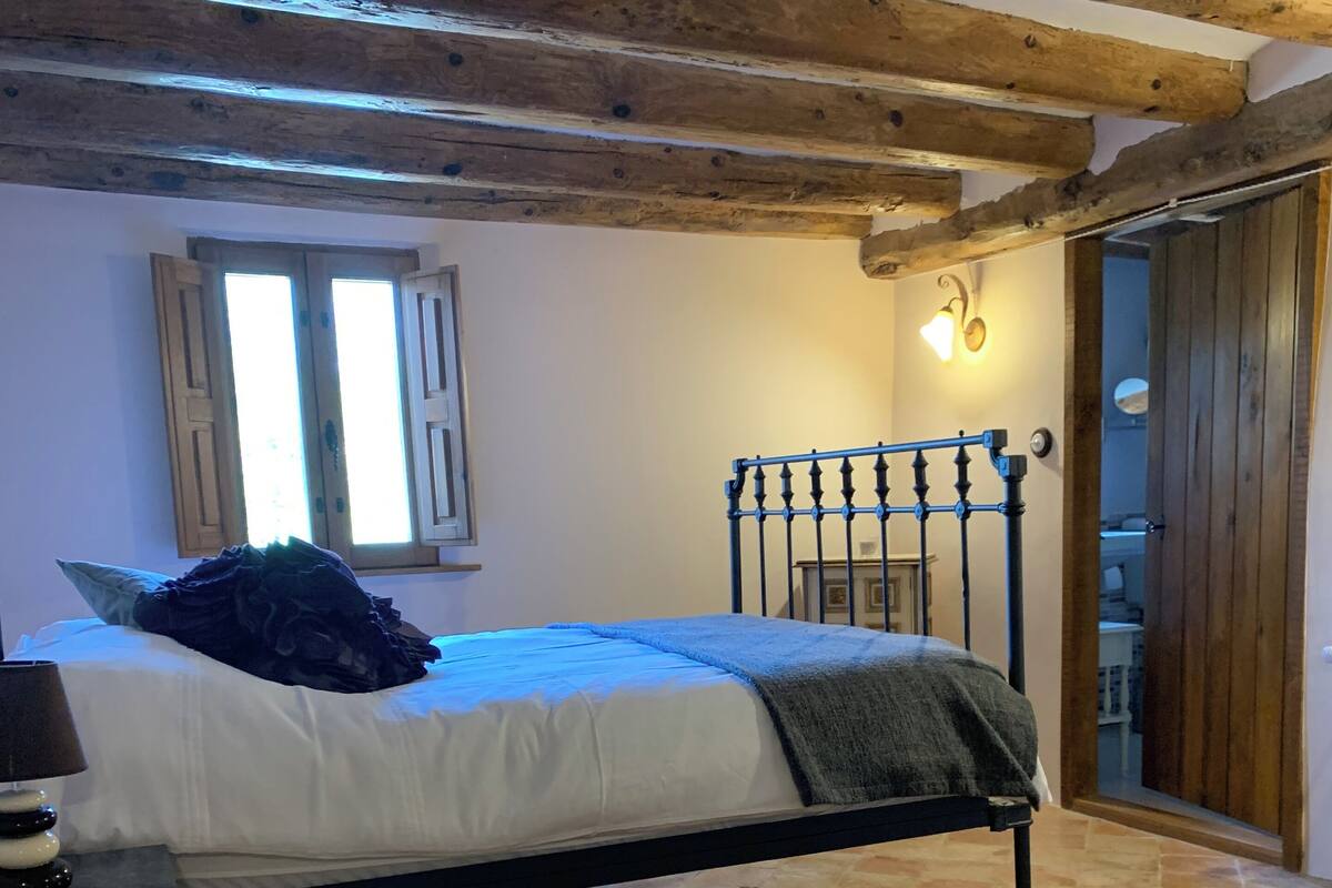 A bedroom with a bed, a nightstand, a window, and a door.