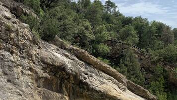 A rocky landscape with a small pond surrounded by trees and a clear sky.