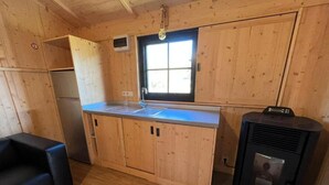 Una cocina compacta con armarios de madera, una estufa integrada, un lavamanos y un ventanal.
