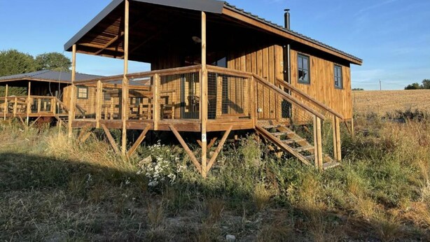 Una cabaña de madera con un porche cubierto y una escalera que lleva a la entrada.