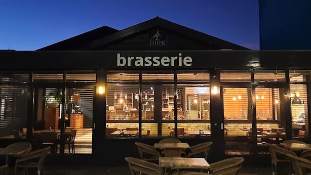An outdoor seating area with tables and chairs in front of a building labeled "brasserie." - De Schildkamp (Asperen)