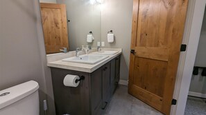 Een badkamer met twee wasbakken, een toilet en een houten deur.