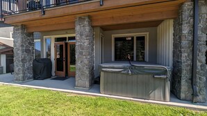 Una casa con fachada de piedra, un patio cubierto y un jacuzzi.