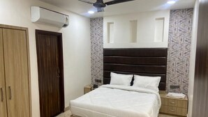 A bedroom with a bed, a ceiling fan, an air conditioner, a wardrobe, and a patterned wall. - D 0101 Cafe and Lounge (Amritsar)