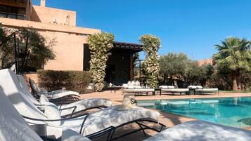 Alberca al aire libre, sombrillas en la alberca y camastros