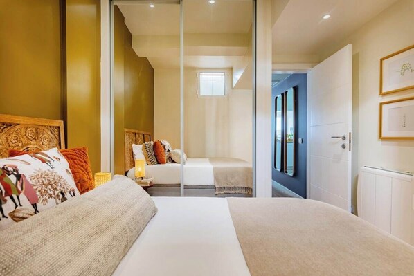 Un dormitorio con dos camas, cabeceros de madera y una mesita de noche con lámpara.