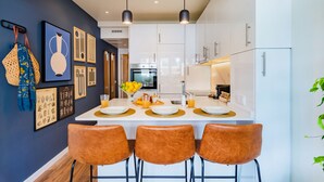 A modern kitchen with white cabinets, a central island with stools, and pendant lighting. - Cascais Modern & Quiet Retreat (Cascais)