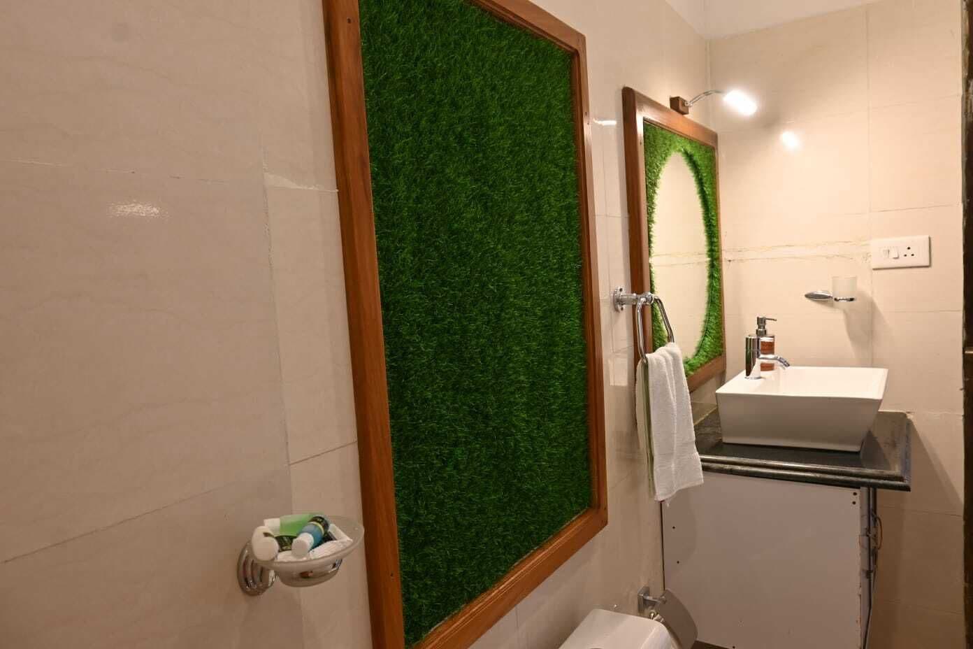 Un baño con pared de césped artificial verde, un lavamanos blanco y un inodoro.