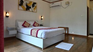 A bedroom with a bed, bedside tables, a wall-mounted air conditioner, and a decorative wall piece. - Placid Garden Resort (Port Blair)