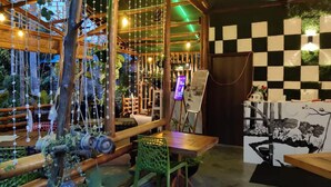 A restaurant with a rustic wooden interior, a checkered wall, and a painting of a tree. - Placid Garden Resort (Port Blair)