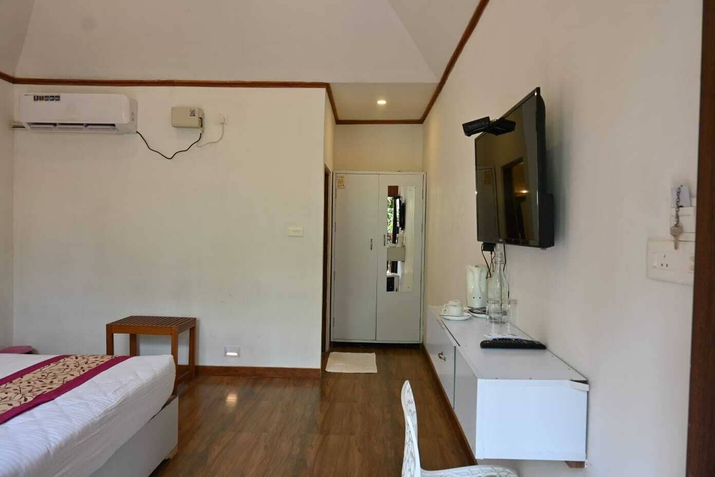 Une chambre d’hôtel équipée d’un lit, d’un bureau avec un ordinateur, d’une télévision et d’un appareil de climatisation.