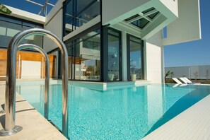 A modern building with a swimming pool, large glass windows, and a metal pool ladder. - Luxury Villa Glass - 200 Meters From The Beach no6 (Chania)