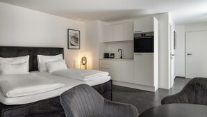 Una habitación de hotel moderna con una cama grande, una kitchenette pequeña y un comedor.