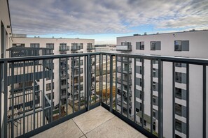 A balcony with a view of modern apartment buildings, metal railings, and a clear sky.