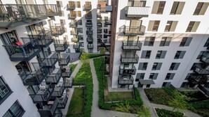 A high-rise residential building with multiple balconies, a central courtyard with greenery, and a modern architectural design. - RentPlanet - Atal City Square (Wroclaw)