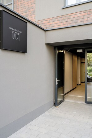 A building entrance with a sign reading "Madalińskiego 101" and a glass door leading inside.