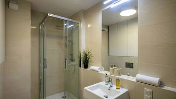 Une salle de bain moderne avec une douche à parois de verre, un lavabo blanc et un miroir au-dessus.