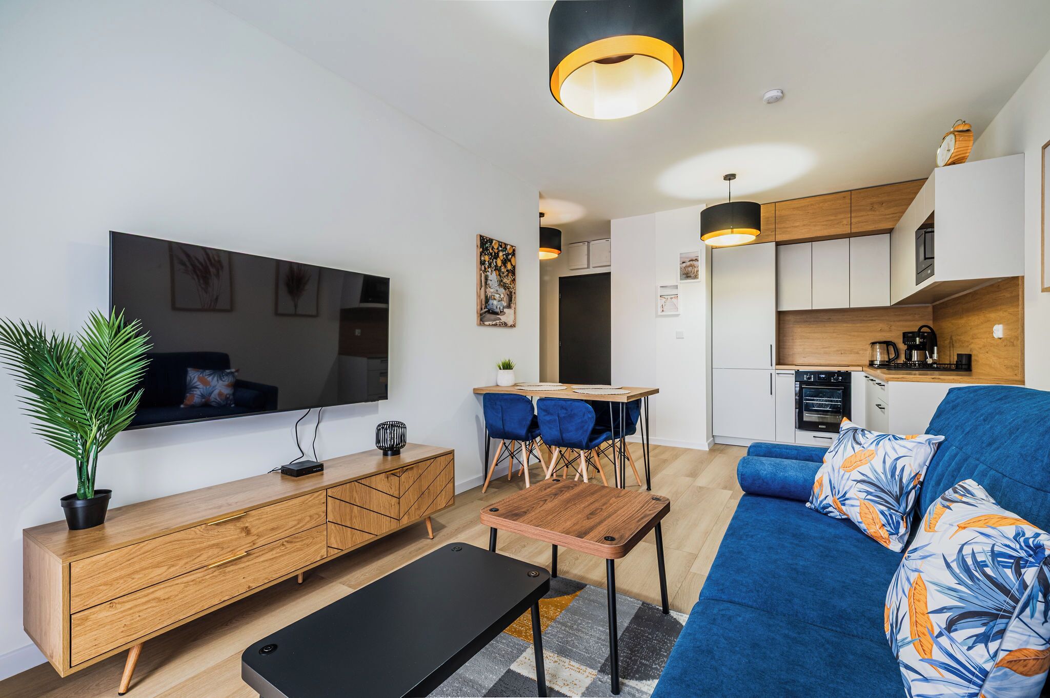 A modern living room with a sofa, a coffee table, a TV, and a dining area with chairs.