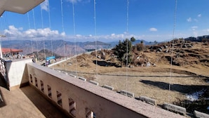 Vista desde un balcón sobre un paisaje montañoso con cielo despejado.
