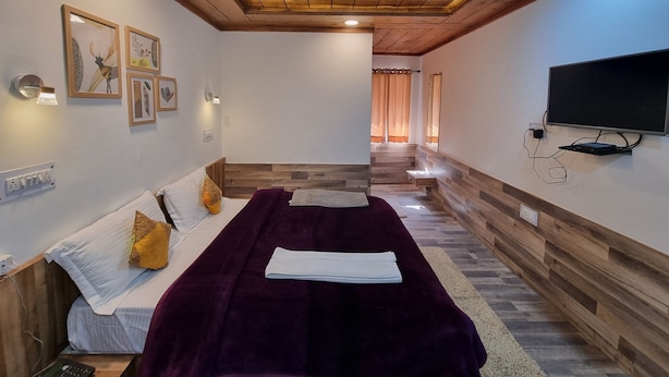 Una habitación con cama, televisión y obras de arte en la pared.