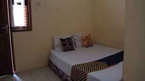 Une petite chambre avec un lit simple, un mur uni, une fenêtre donnant sur un paysage agréable et un sol carrelé.