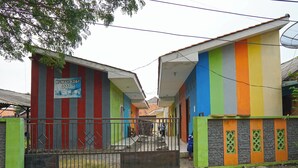 Un bâtiment aux couleurs vives, sur lequel on peut lire l’inscription « Rumah Kecil Arah ».