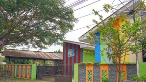 Une maison aux couleurs vives, avec un toit en métal, une porte et un arbre devant.