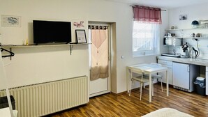 Une cuisine de taille réduite avec un plan de travail blanc, une petite table à manger et un radiateur.