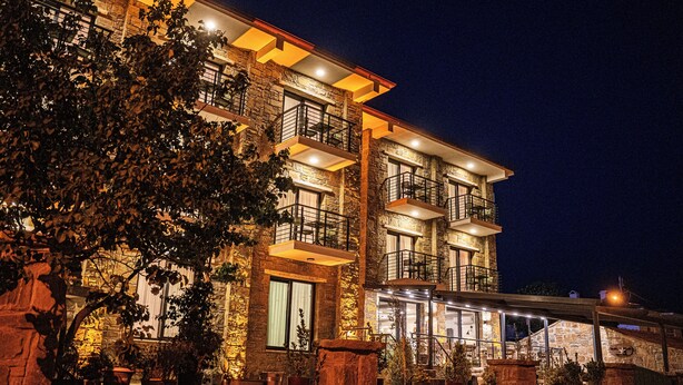 A multi-story hotel with stone facade, balconies, and outdoor seating areas. - Maslin Otel (Gökçeada)