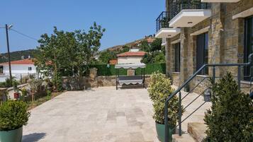 A courtyard with a stone floor, a pergola, and potted plants.