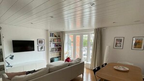 Moderni olohuone, jossa on sohva, ruokapöytä ja televisio.