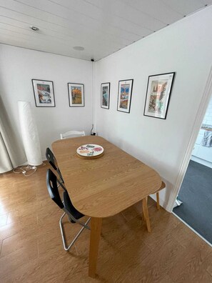 A conference room with a wooden table, four chairs, and four framed pictures on the wall. - 2BD Flat With Views of Canary Wharf - Rotherhithe (London)