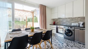 A modern kitchen with a washing machine, a dining area with a table and chairs, and a view of the outside. - Bela Vista A in Lisboa (Lisbon)