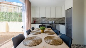 A dining area with a wooden table, black chairs, and woven placemats. - Bela Vista A in Lisboa (Lisbon)
