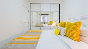 A bedroom with a bed, a mirror, and a sliding door. - Bela Vista A in Lisboa (Lisbon)