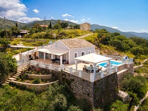 A villa with a pool, stone walls, and a patio area.