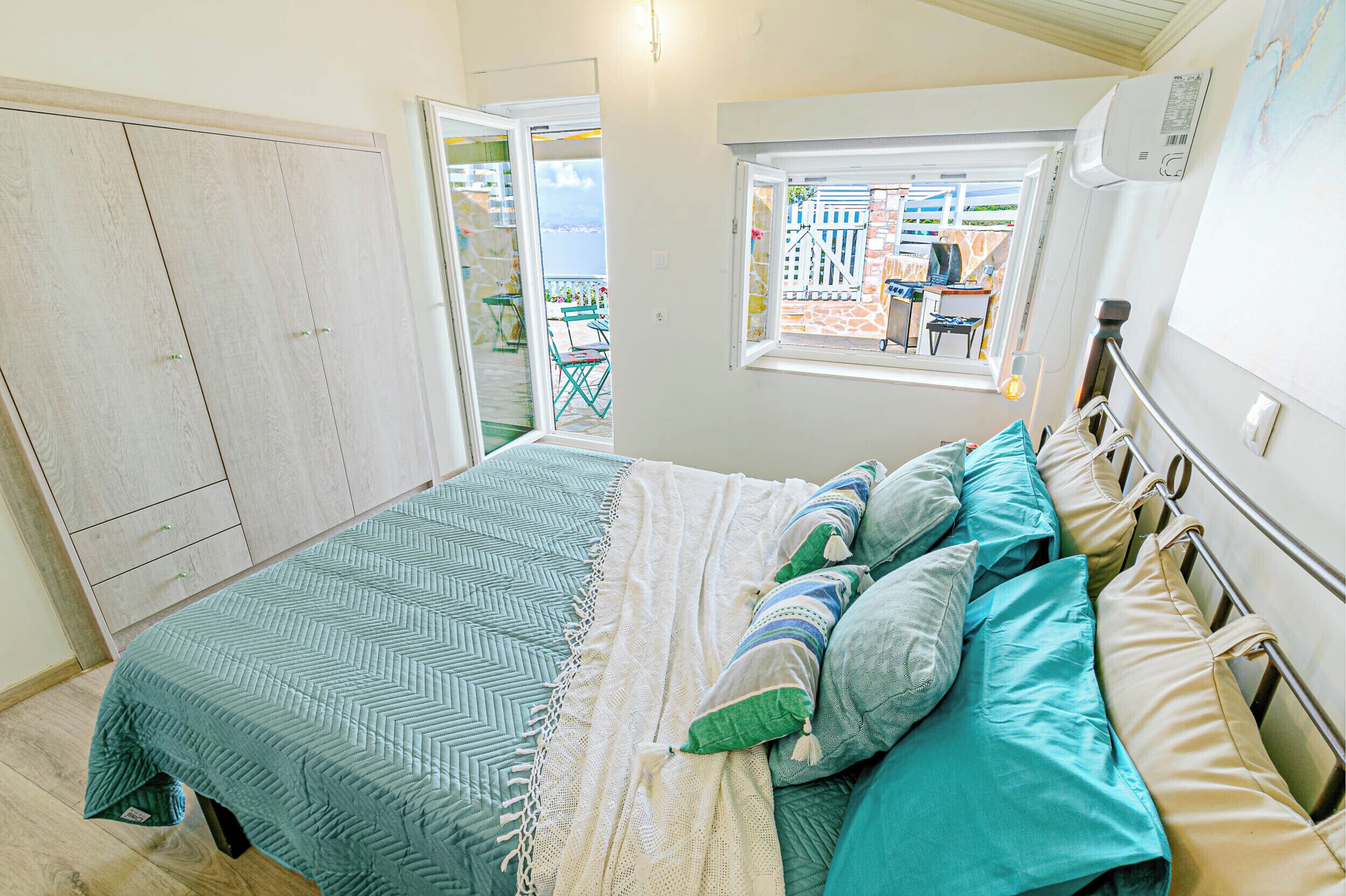 A bedroom with a bed, a wardrobe, and a window with a view of the outside.