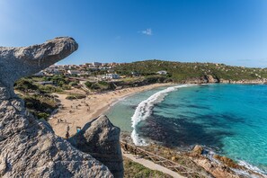 A coastal town with a beach, rocky coastline, and buildings in the background. - Relaxing Cristal Blu Studio Sleeps 4 Persons (Santa Teresa di Gallura)
