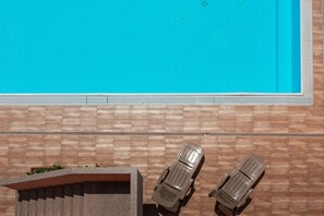 Una piscina con dos sillas de descanso y un muro de piedra.