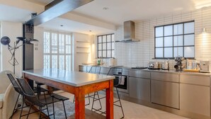 Une cuisine moderne avec une table et des chaises en bois, des appareils électroménagers en acier inoxydable et une grande fenêtre.