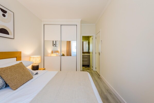 A hotel room with a bed, nightstand, lamp, and a door leading to a hallway. - Bela Vista B in Lisboa (Lisbon)